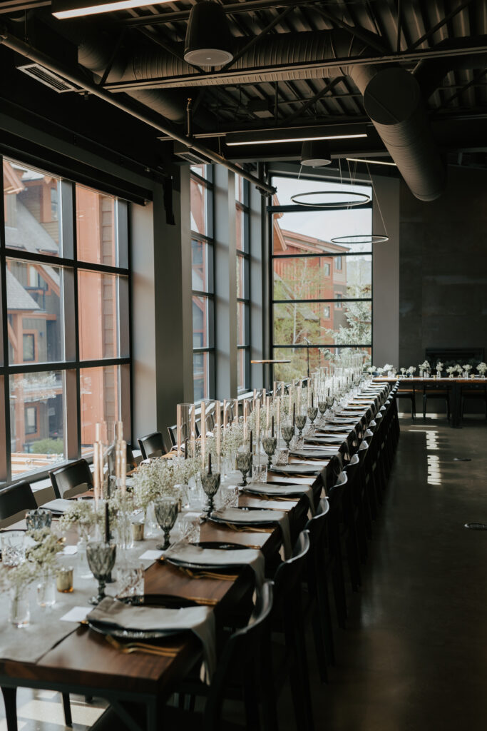 Long reception table with elegant place settings, candles, and natural light inside the Mainspace venue in Canmore