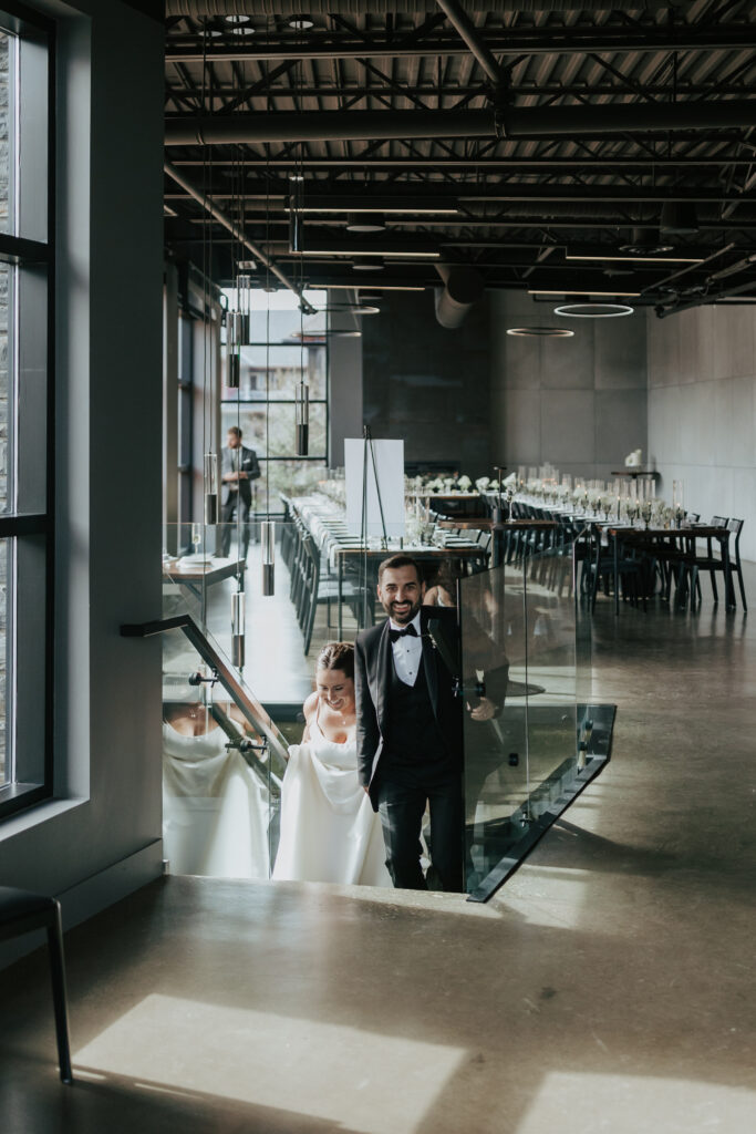 Bride and groom walking up the stairs into their modern wedding reception at Mainspace in Canmore
