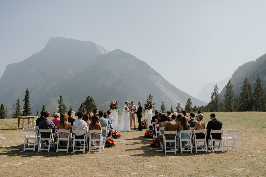 Bride and groom exchanging vows during an outdoor ceremony with mountains in the background