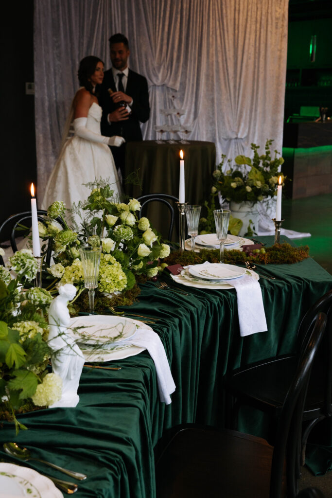 Bride and groom pouring champagne into a stacked coupe glass tower during their reception celebration